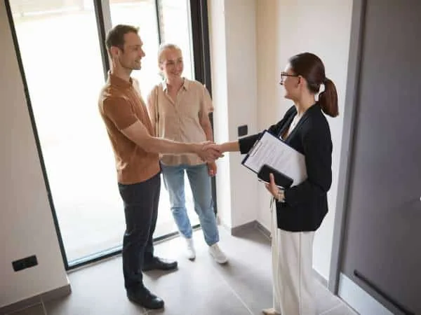 A happy couple is buying a home in Sofia and shake hands with a real estate agent.