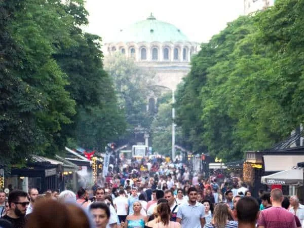 The boulevard Vitosha in Sofia by day, crowded, with a church in the background.