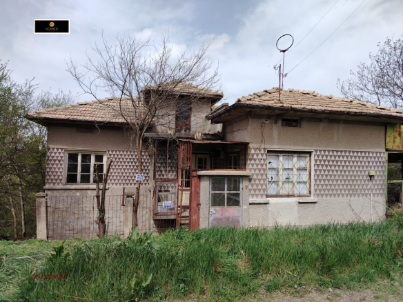 Abandoned two-storey house with tile roof and deteriorated facade