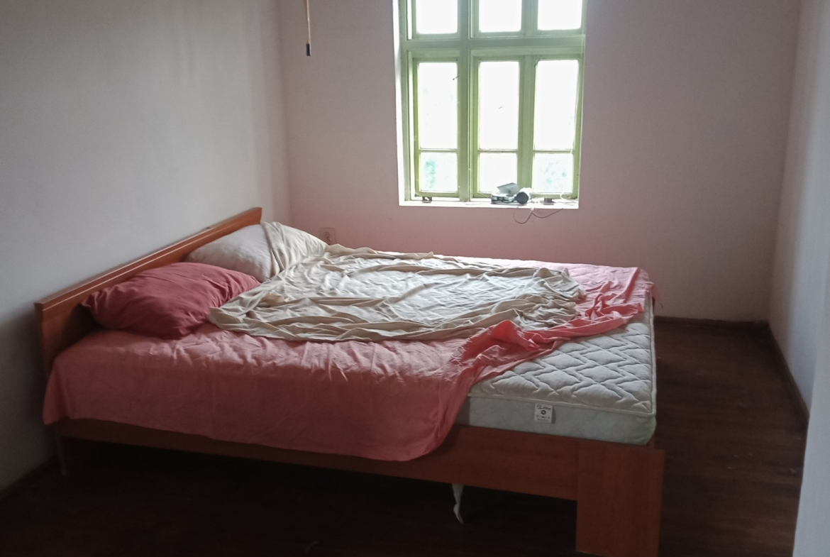 Спална стая с розово спално бельо и дървени греди