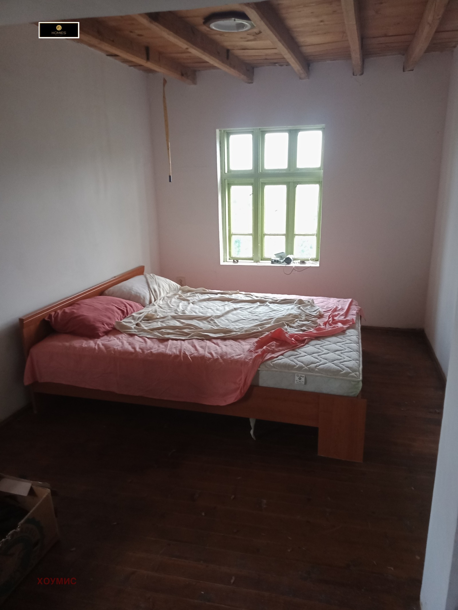 Спална стая с розово спално бельо и дървени греди