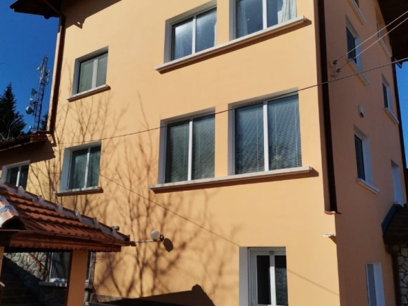 Жълта тристайна къща с кафяв покрив