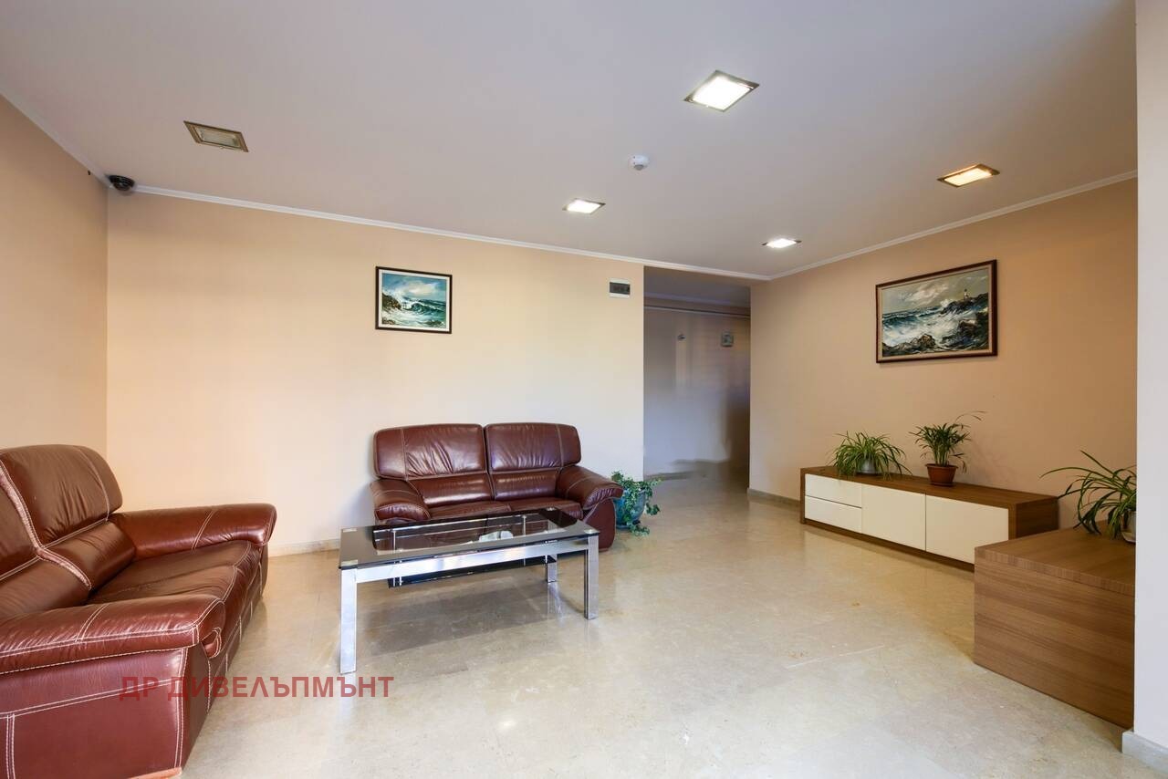 Фоайе на сградата с кожен диван, фотьойл, стъклена маса и асансьор