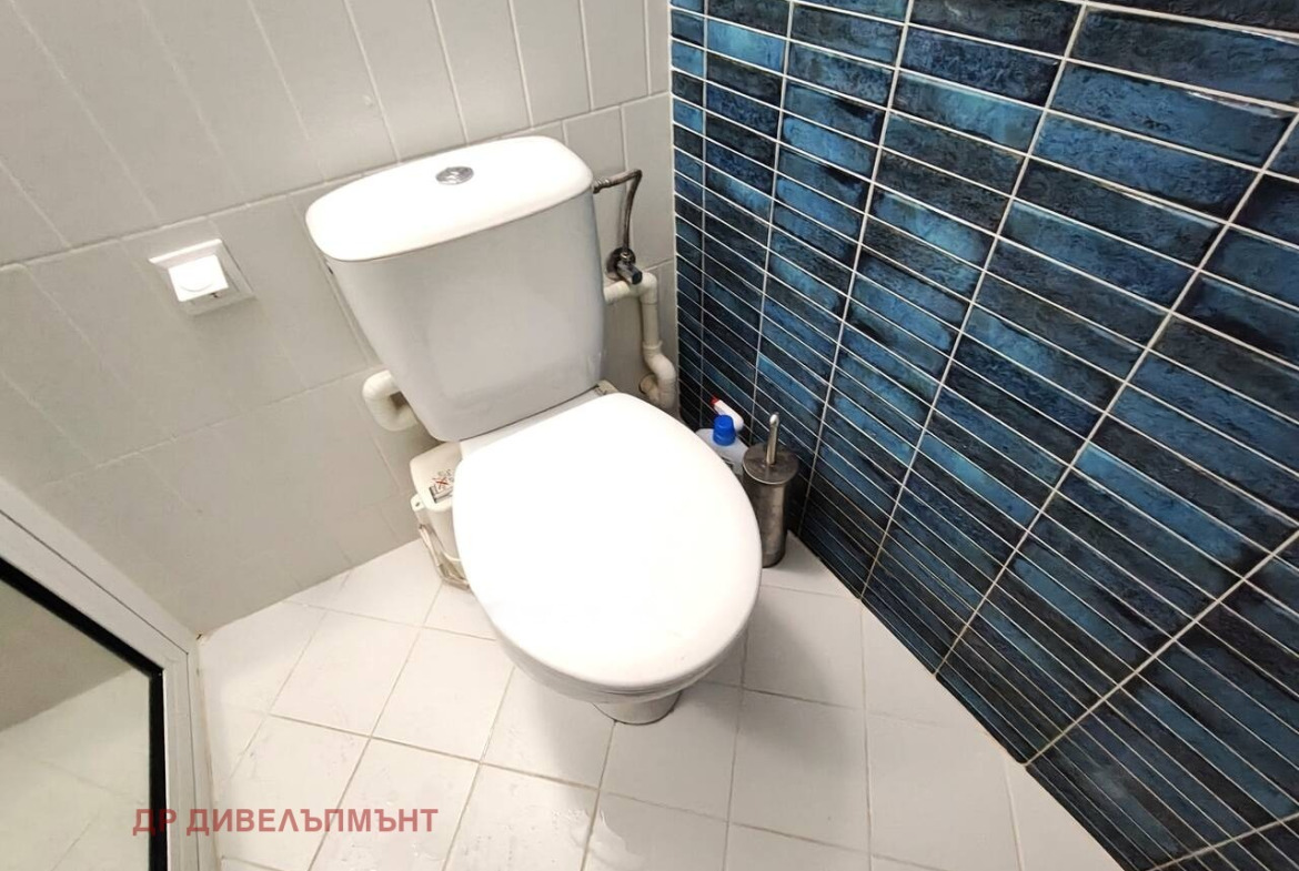 Toilet with white ceramic bowl and blue tiled accent wall