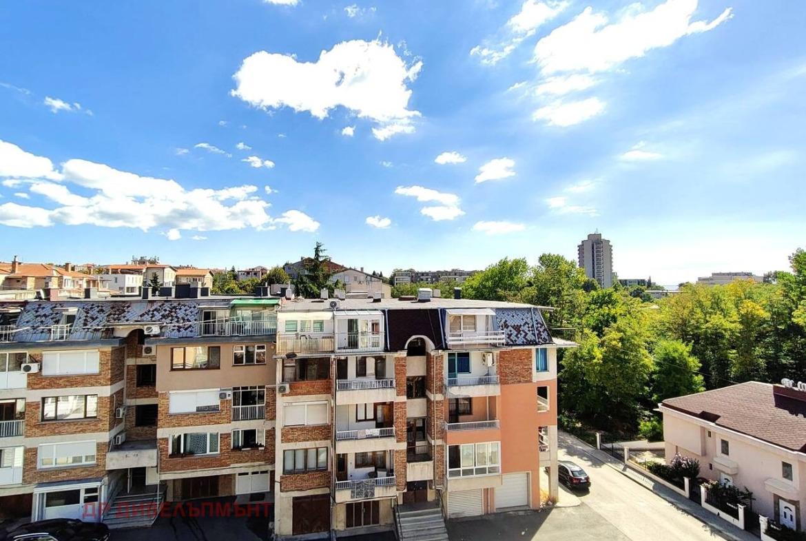 View from balcony over residential buildings and green trees