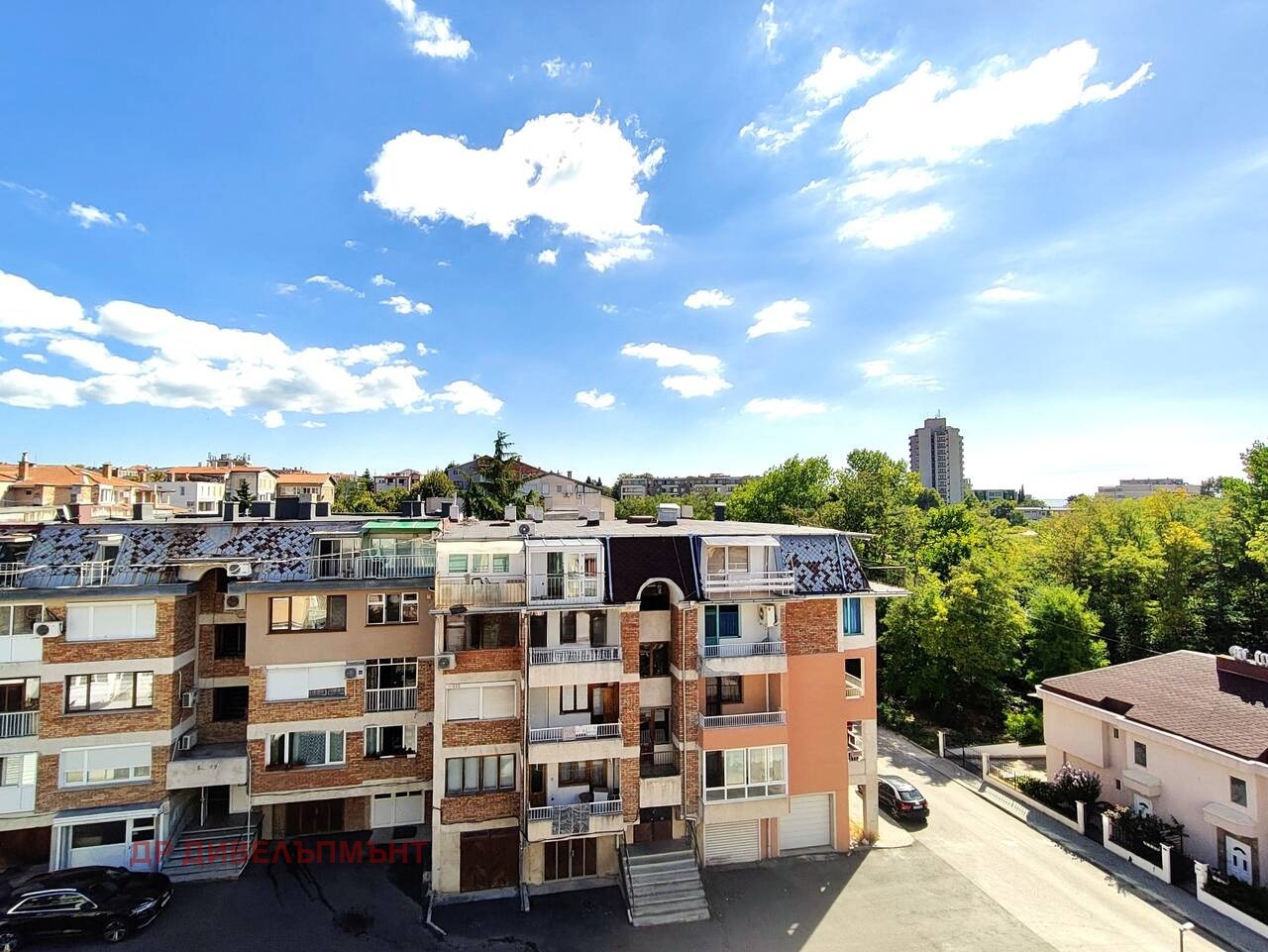 View from balcony over residential buildings and green trees
