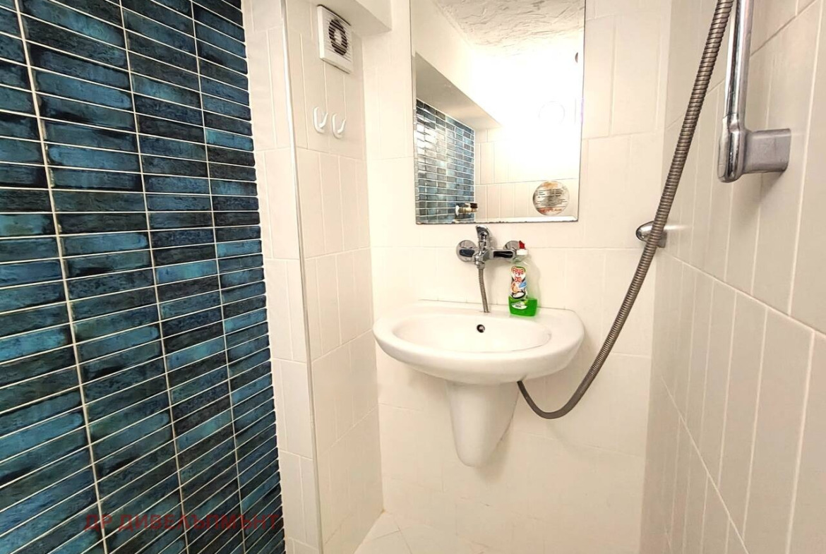Bathroom with wall-mounted sink, shower head, and blue tiled wall