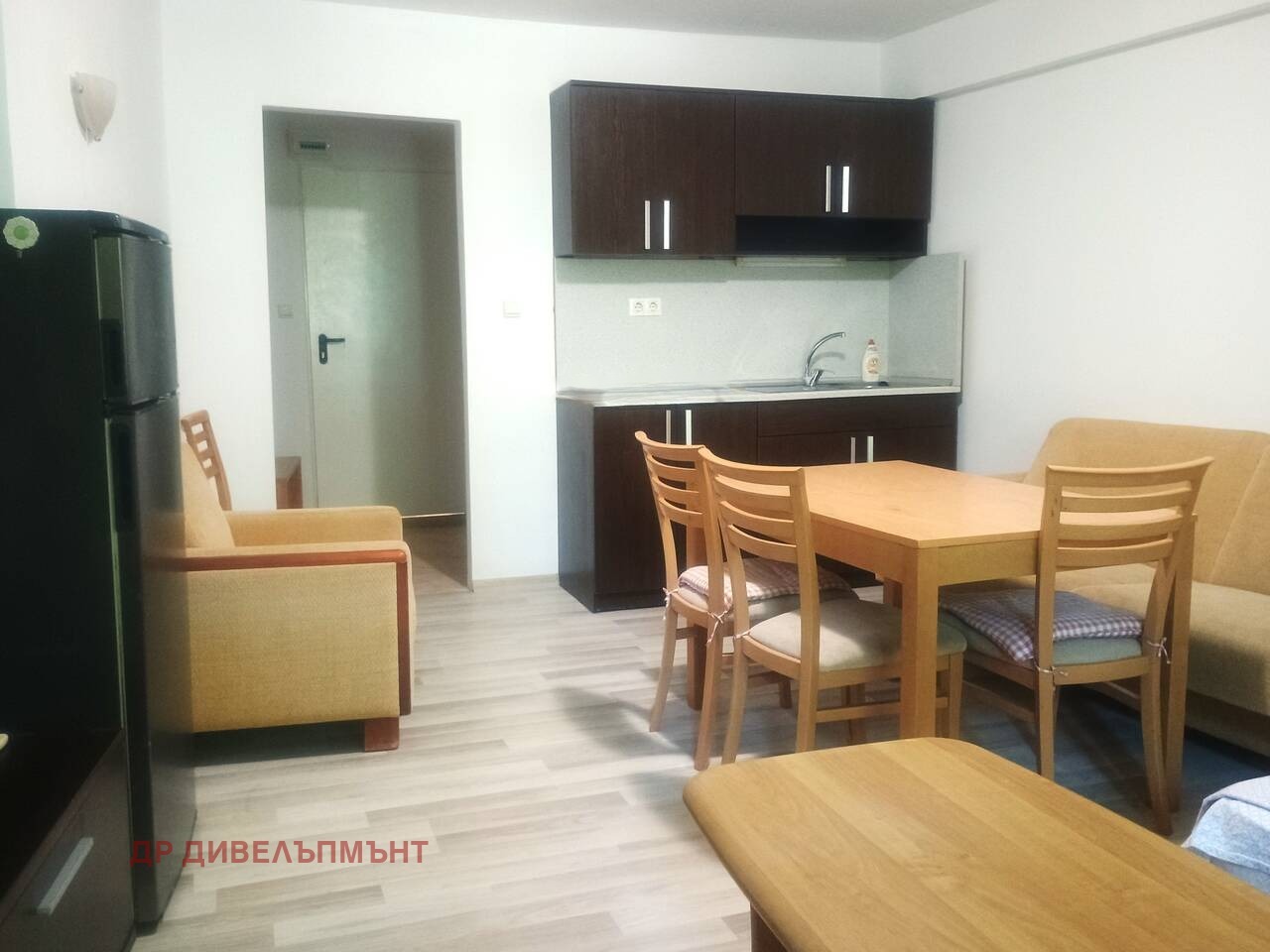 Дневна зона с маса за хранене, столове, диван и кухненски модул
