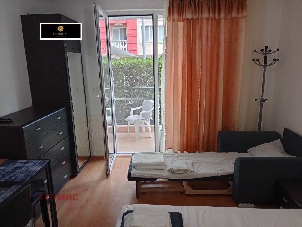 ednostaen-apartament-39-kvm-prodava-slanchev-bryag-obzaveden-500m-plyazh-2 Хол с балкон, черна мебел и оранжеви завеси