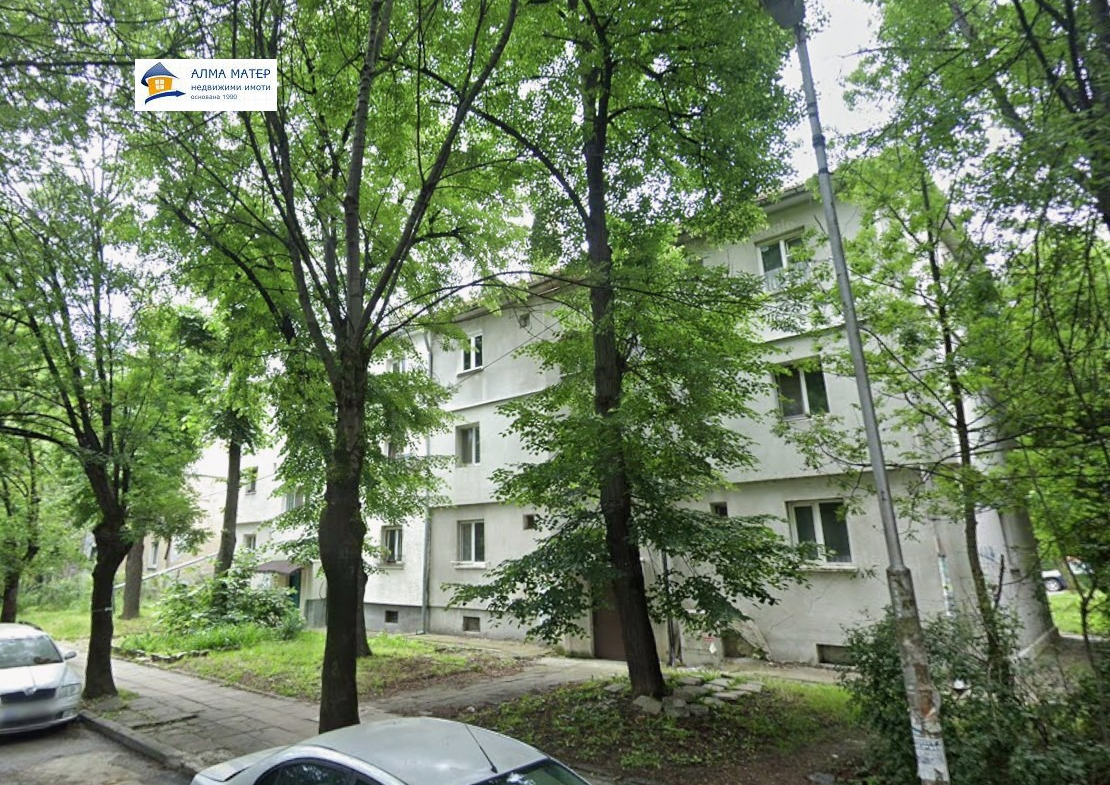 Four-story residential building surrounded by green trees