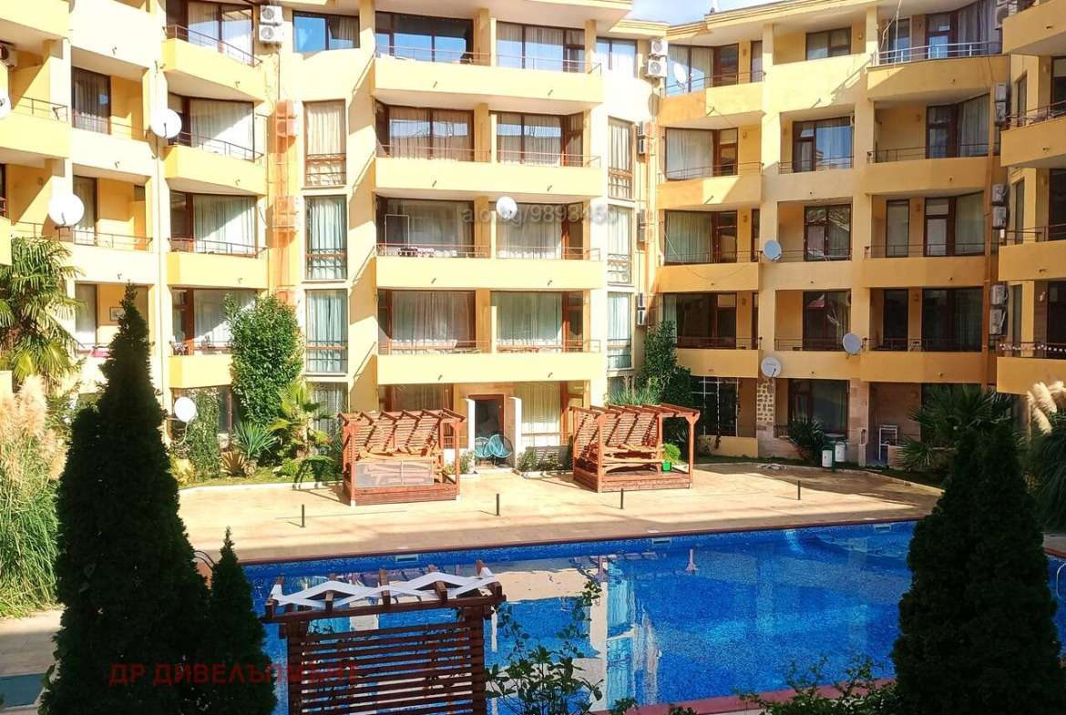 Yellow apartment complex with blue swimming pool below