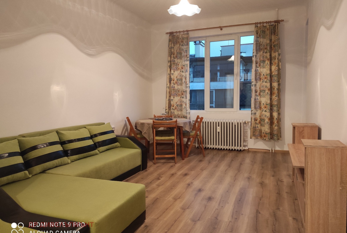 Spacious living room with green sofa and dining area