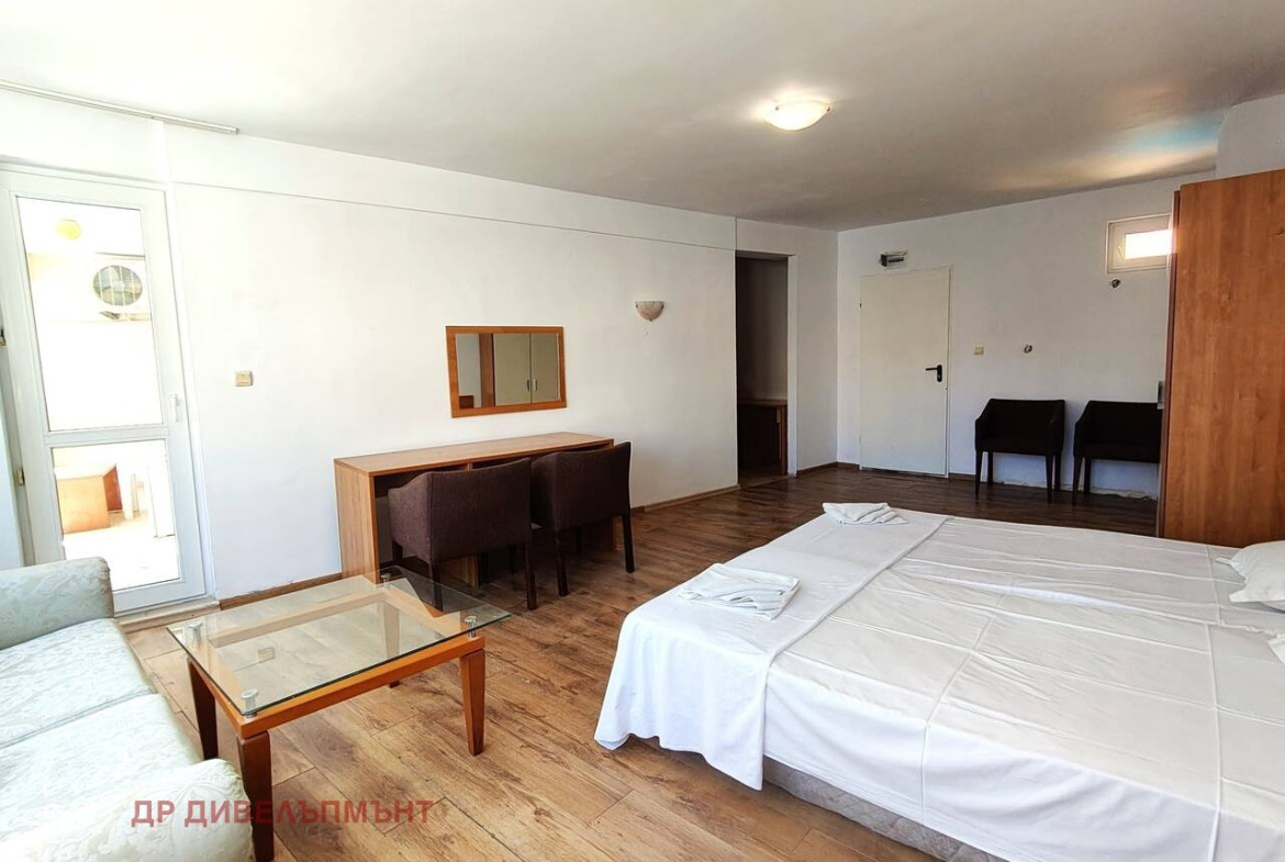 One-Bedroom apartment in Nessebar with double bed, sofa, glass coffee table, desk, and wood-effect floor
