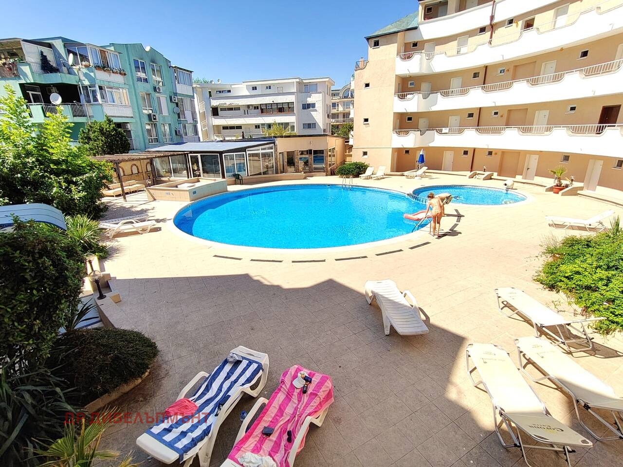 Outdoor swimming pool with sun loungers surrounded by residential buildings