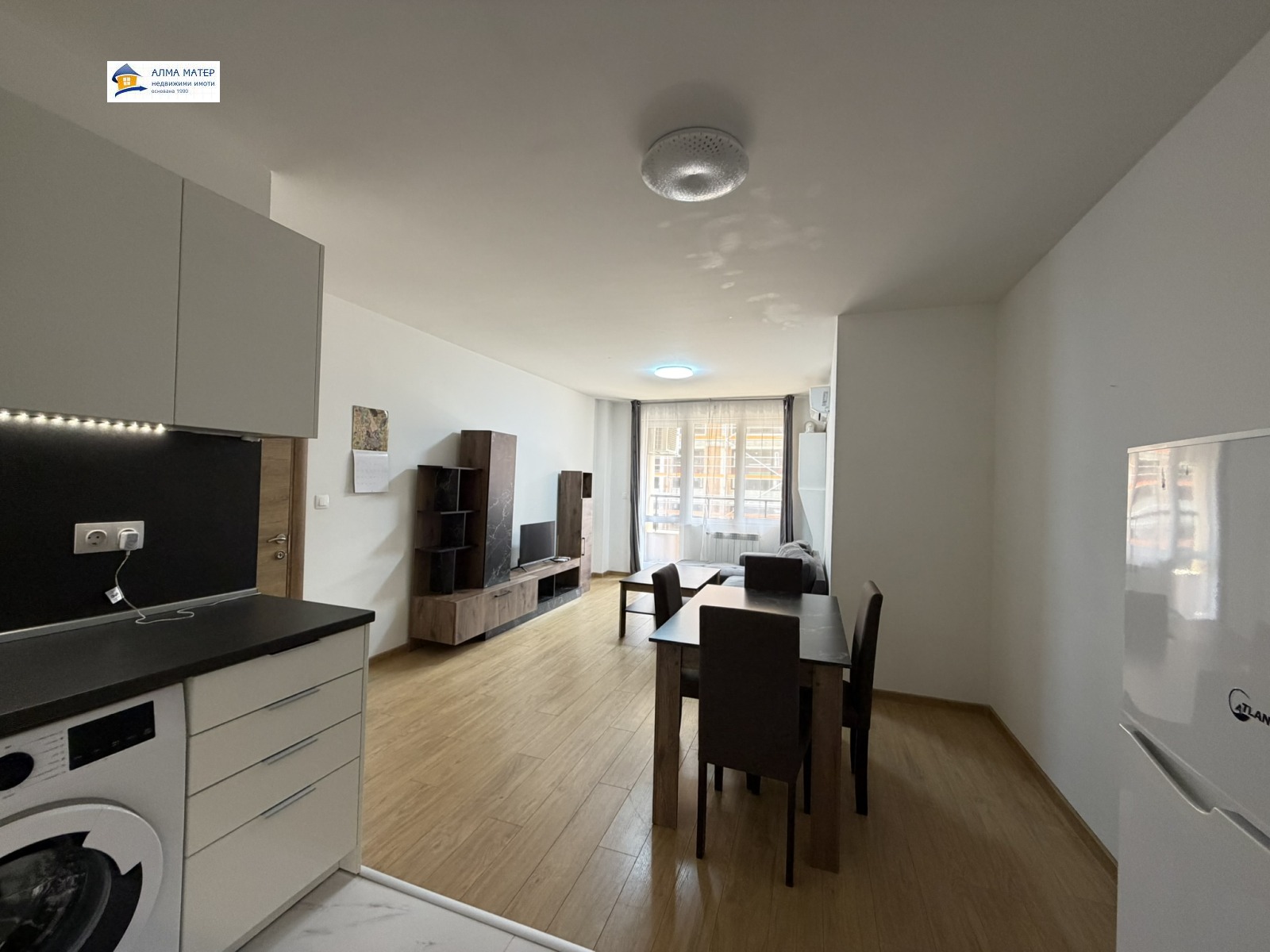 dvustaen-apartament-81-kvm-pod-naem-manastirski-livadi-panoramna-gledka-4 Просторна кухня-дневна с бял шкаф и черен плот
