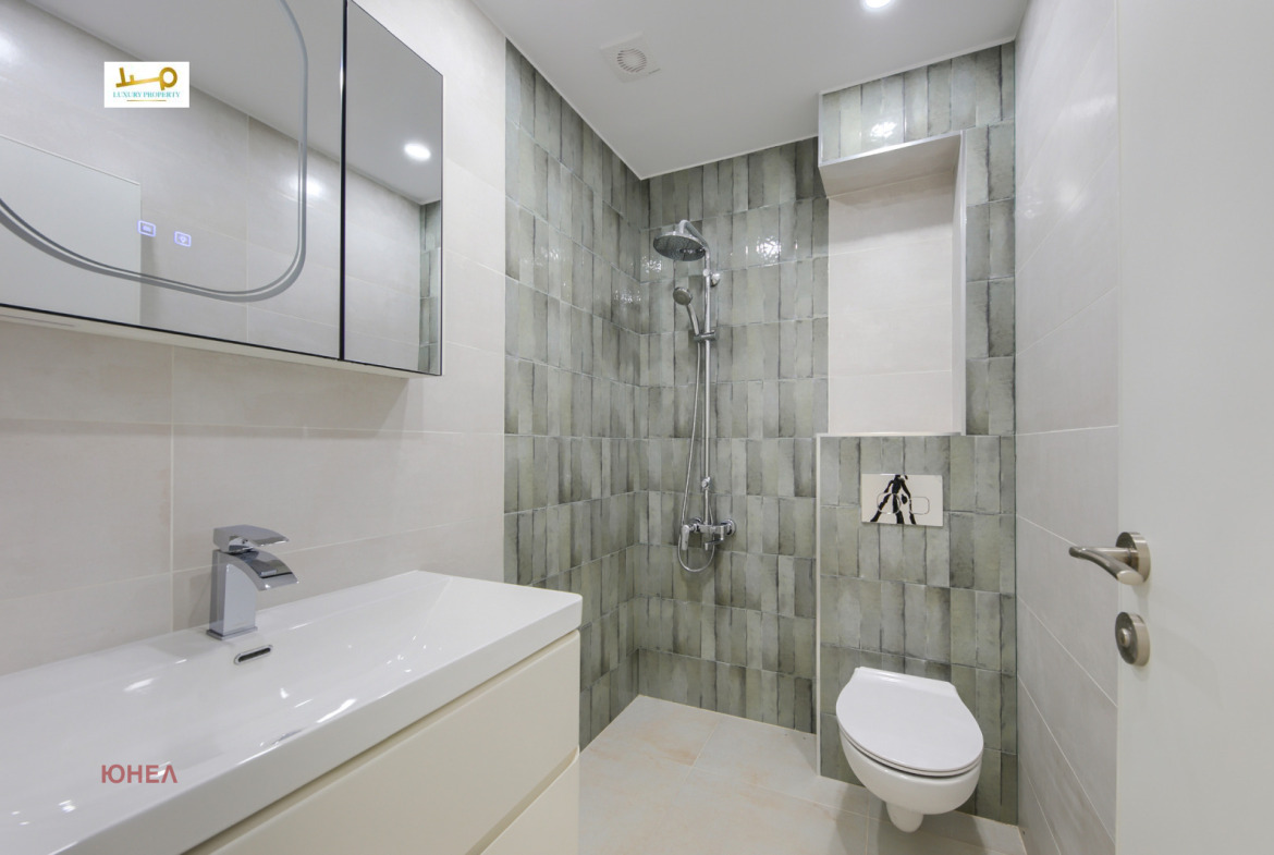 Bathroom with shower, wall-hung toilet, sink, mirror cabinet, green tiles