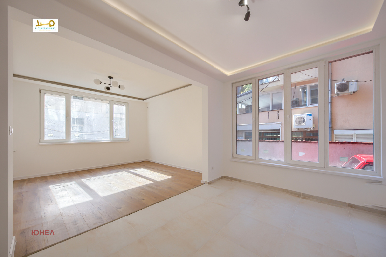 Bright living room with two windows, wood floor, white walls