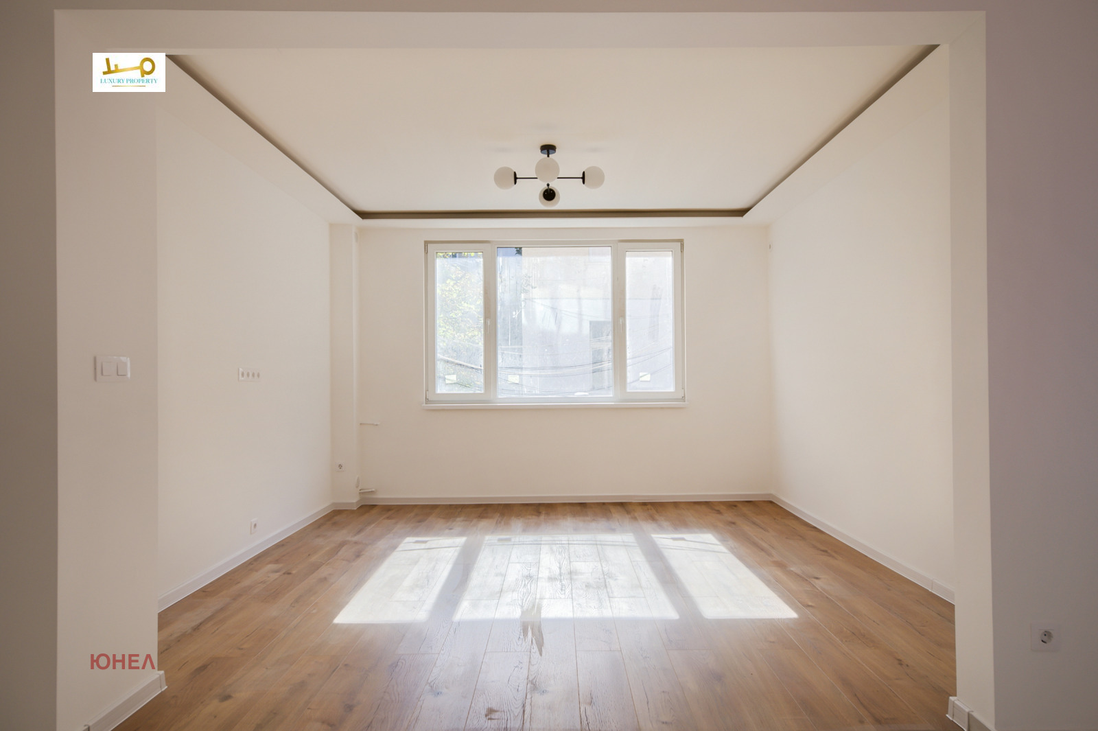 Empty room with wood floor, triple window, ceiling light fixture