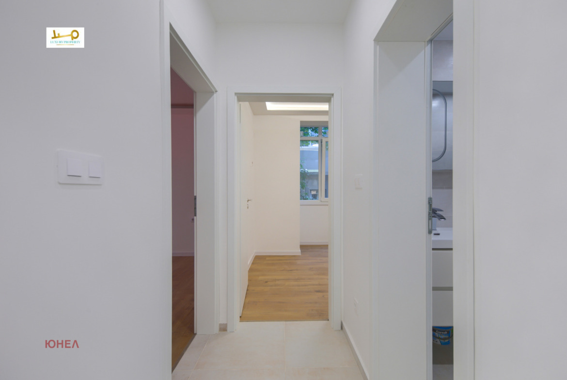 Hallway with three doorways leading to rooms and bathroom, tile floor, white walls