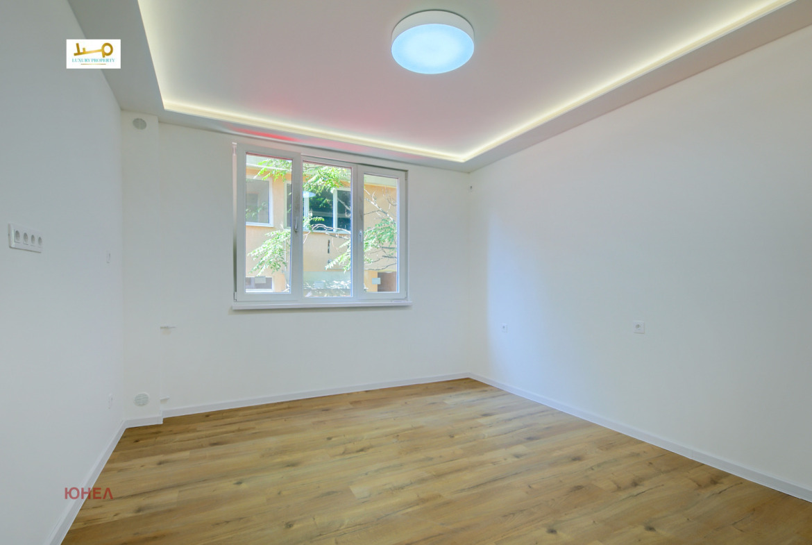 Bedroom with wood floor, double window overlooking courtyard, round ceiling light, LED cove lighting