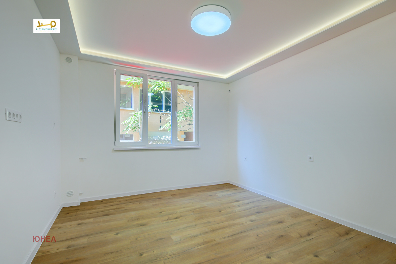 Bedroom with wood floor, double window overlooking courtyard, round ceiling light, LED cove lighting