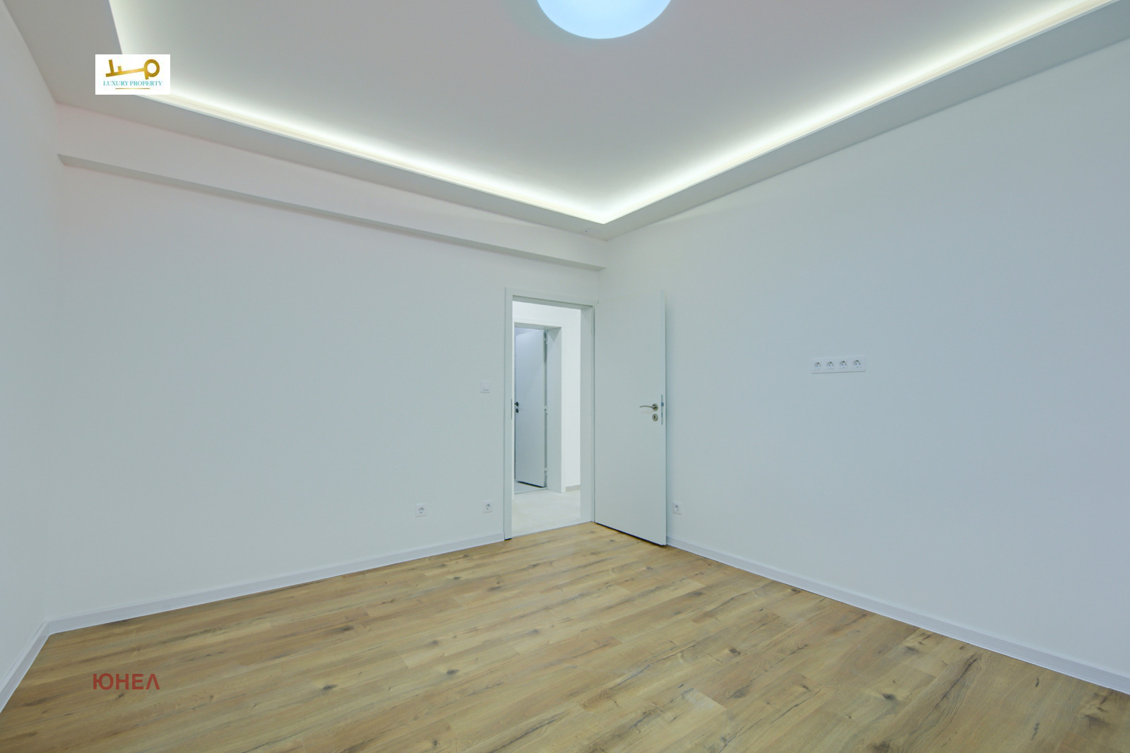 Empty bedroom with wood floor, LED ceiling trim, white door