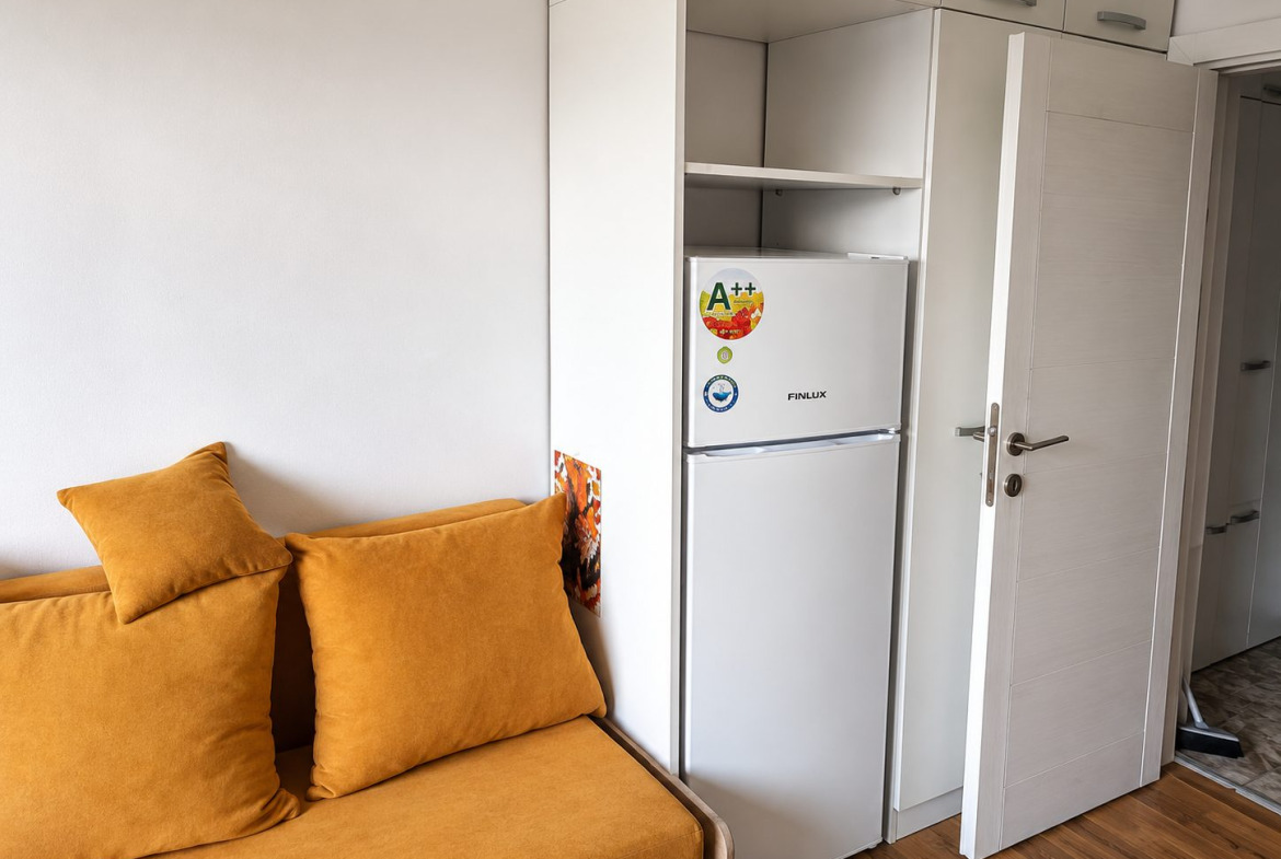 ednostaen-apartament-25-kvm-prodazhba-pavlovo-sofia-maze-4 Хол с оранжев диван и шкаф с часовник