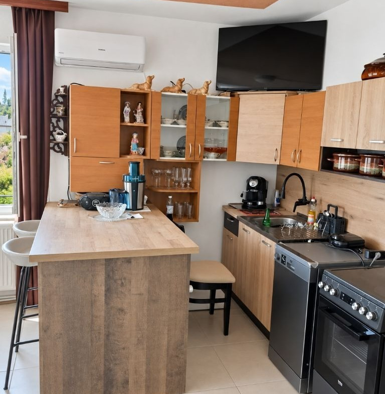 Kitchen with wooden island counter, upper cabinets, open shelves with glassware, and gas stove