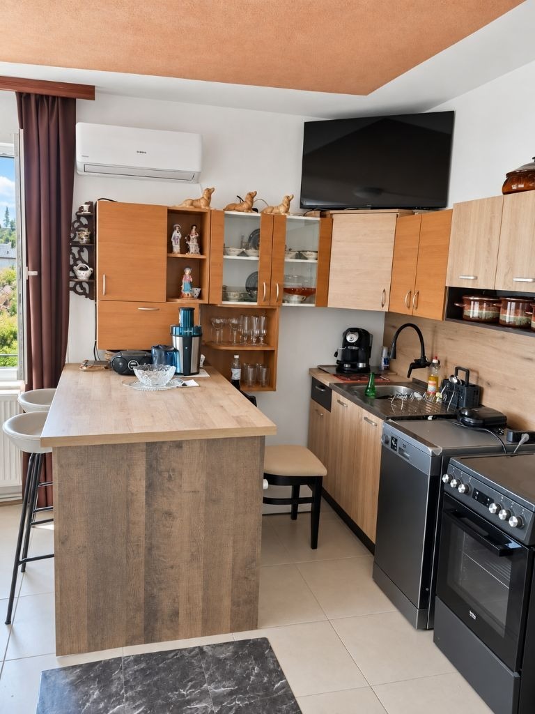 Kitchen with wooden island counter, upper cabinets, open shelves with glassware, and gas stove