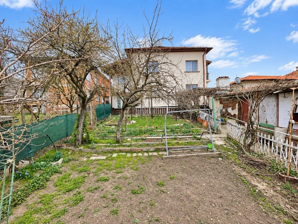 Large garden with fruit trees, vegetable beds, and two-storey house in background