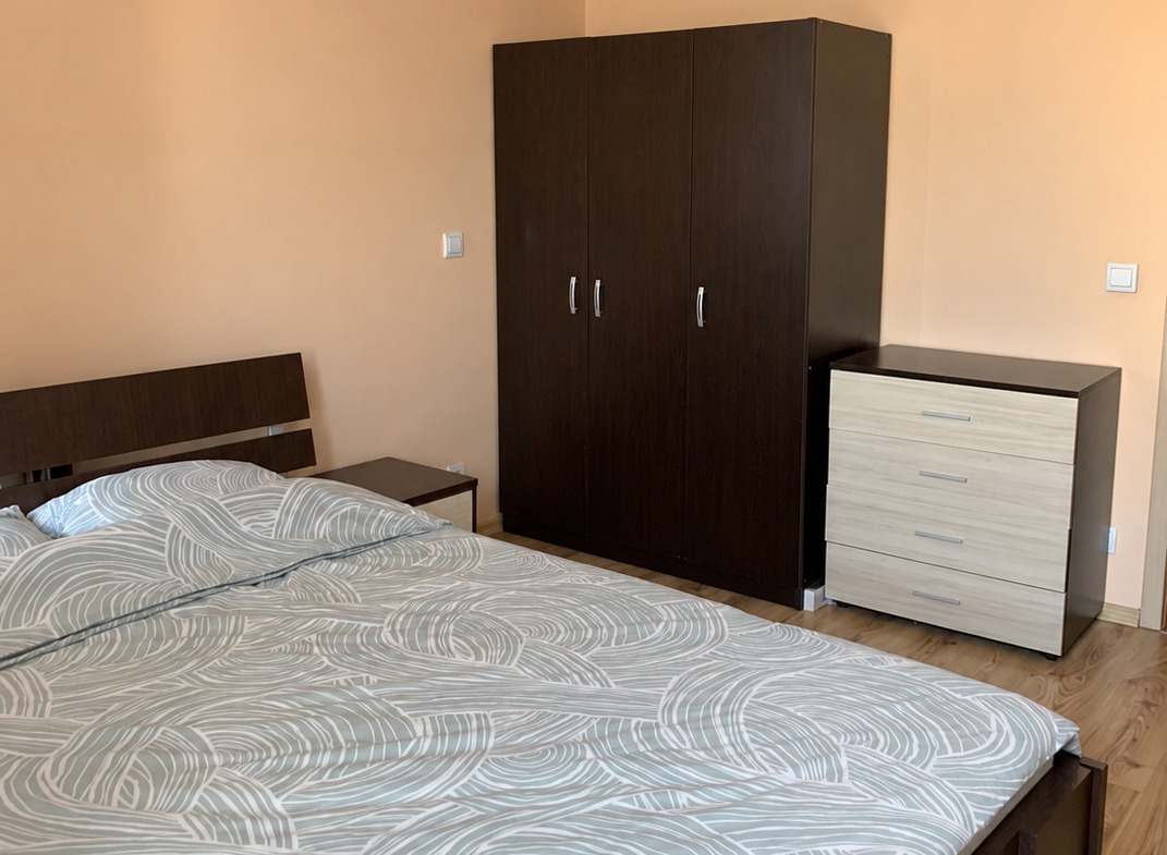 tristaen-apartament-108-kvm-pod-naem-manastirski-livadi-sofiya-napalno-obzaveden-5 Спалня с тъмни мебели дървен под и балкон