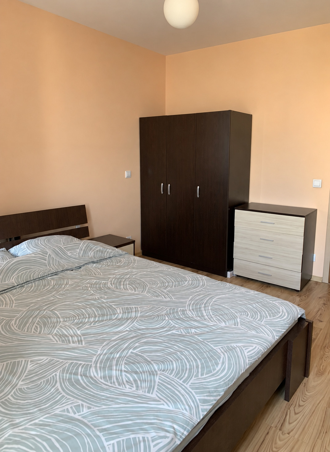 tristaen-apartament-108-kvm-pod-naem-manastirski-livadi-sofiya-napalno-obzaveden-5 Спалня с тъмни мебели дървен под и балкон