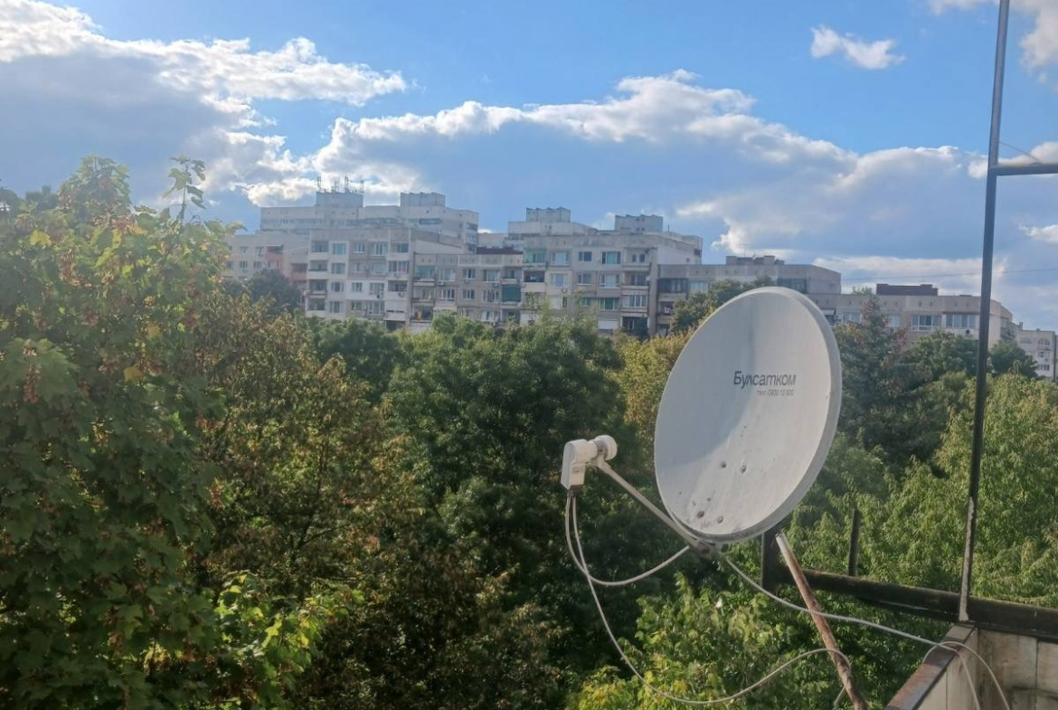 tristaen-apartament-90-sqm-pod-naem-lyulin-3-sofia-obzaveden-sklad-4 Изглед от тераса със сателитна чиния, зелени дървета и жилищни блокове