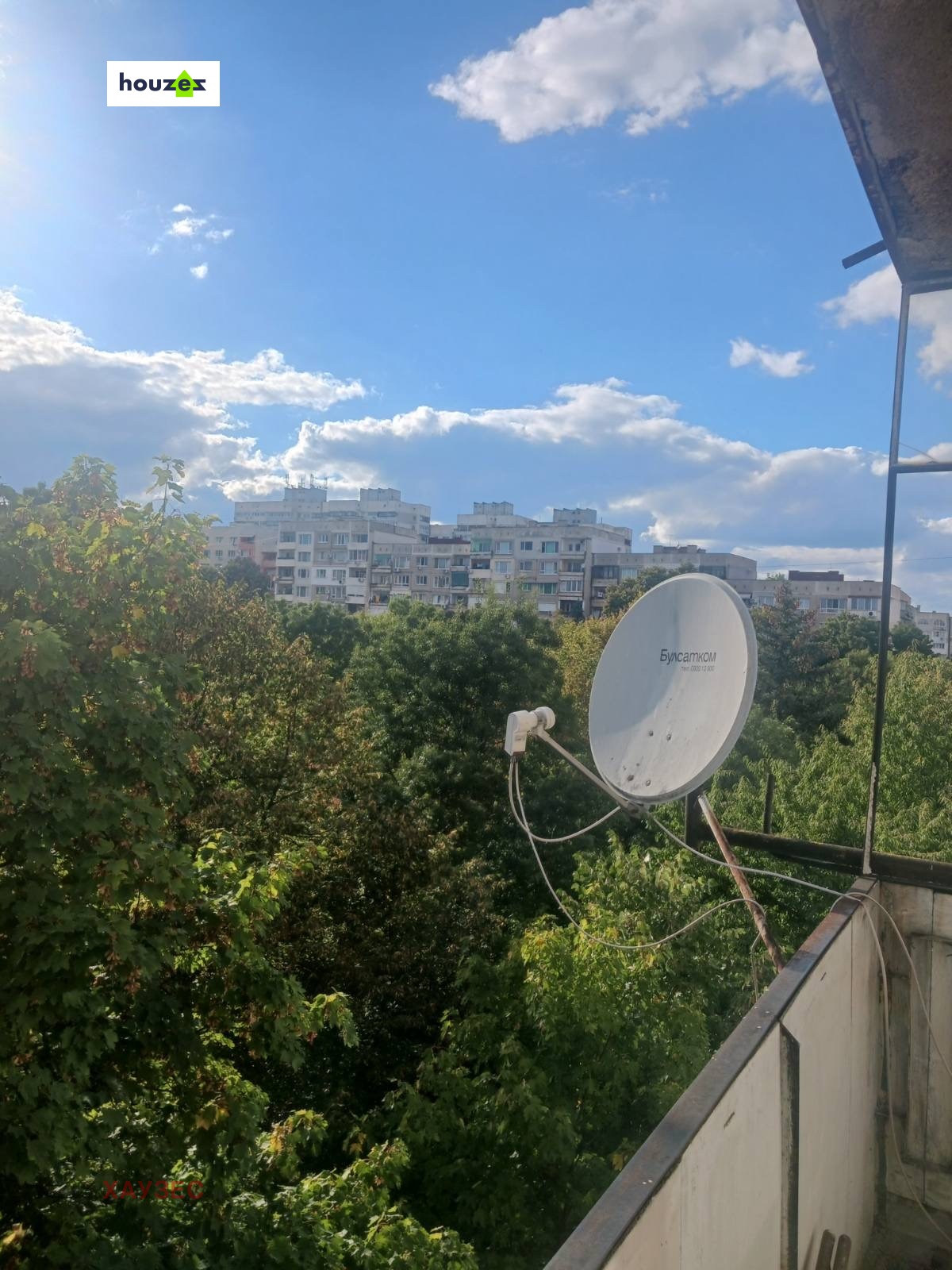 tristaen-apartament-90-sqm-pod-naem-lyulin-3-sofia-obzaveden-sklad-4 Изглед от тераса със сателитна чиния, зелени дървета и жилищни блокове
