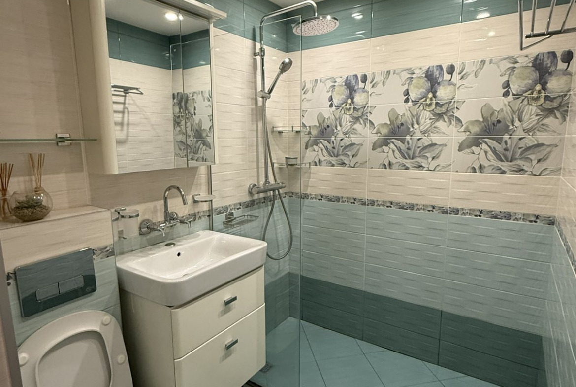 Bathroom with shower, toilet, vanity unit, teal tiles