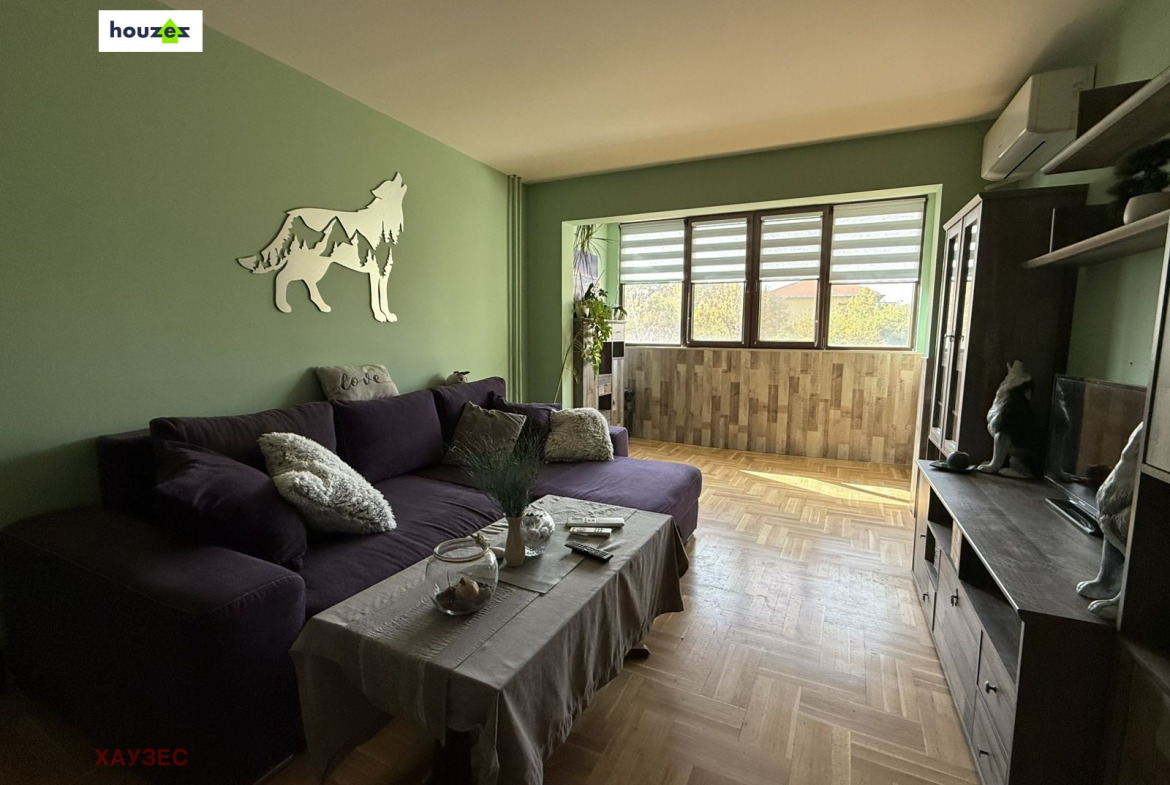 Living room with purple corner sofa, wolf wall decor, green walls, parquet floor