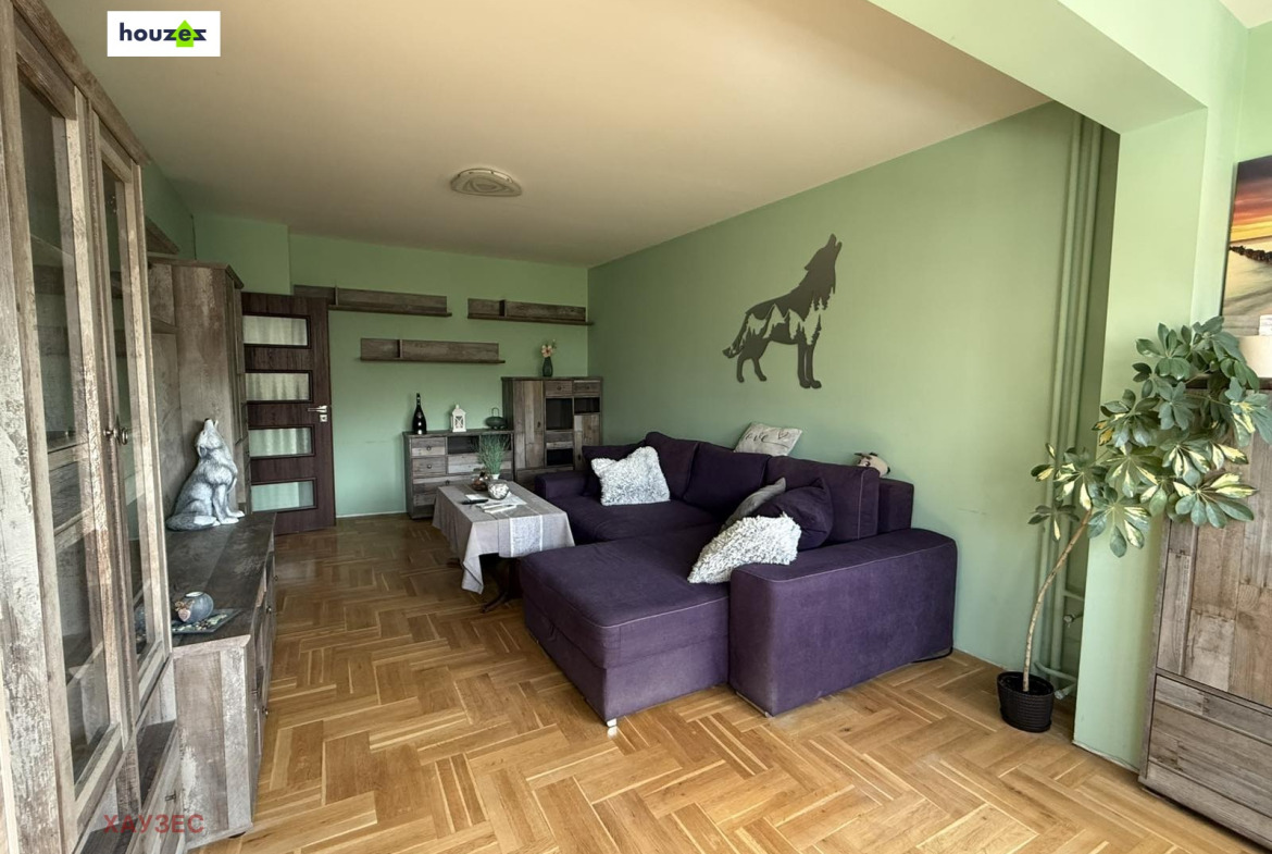 Living room with purple sectional sofa, parquet floor, green walls