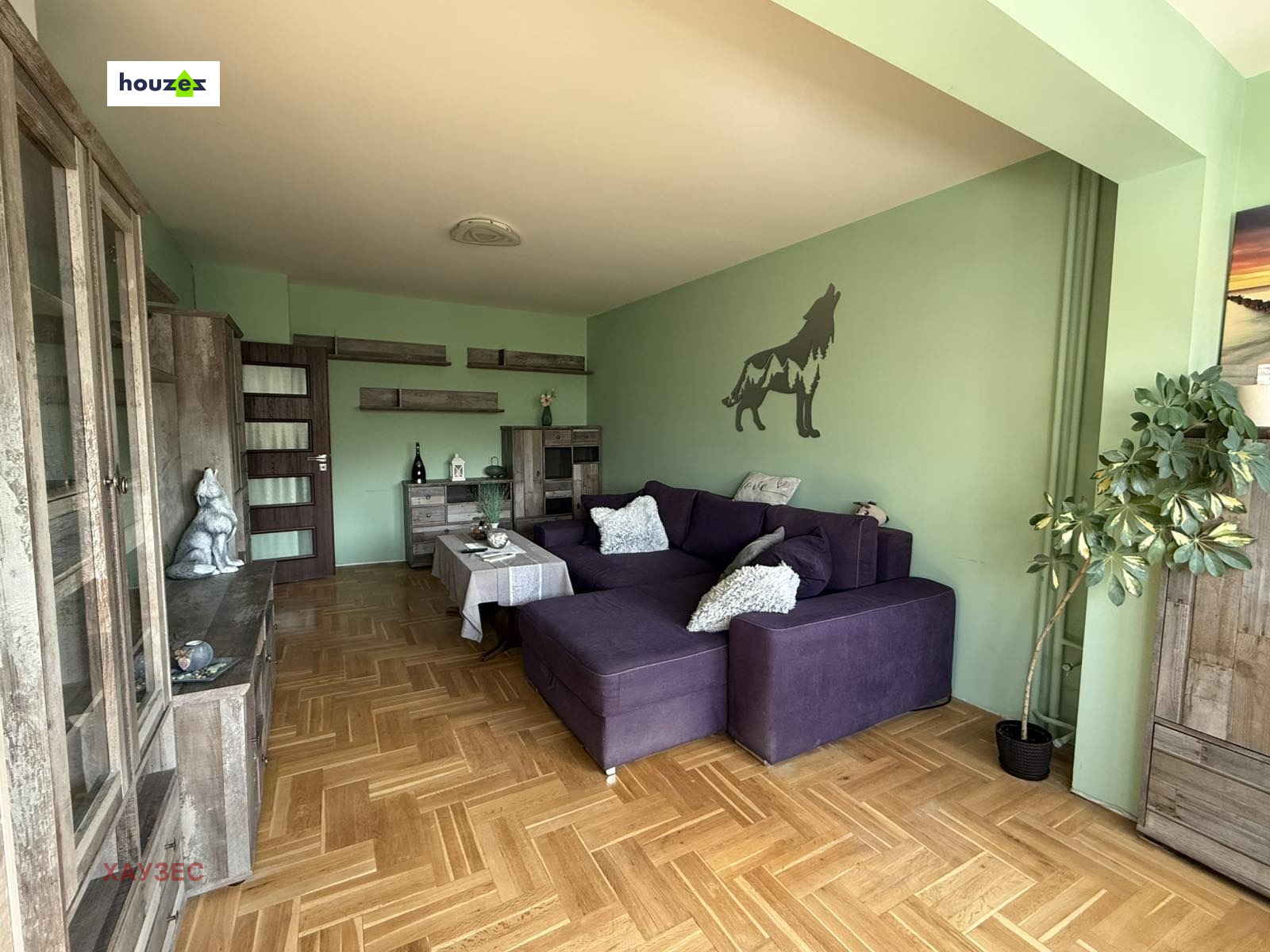 Living room with purple sectional sofa, parquet floor, green walls