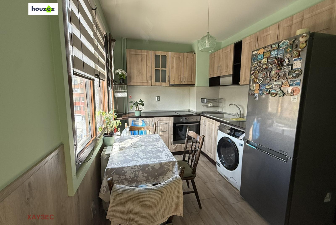Kitchen with wood cabinets, black countertop, dining table, washing machine, refrigerator