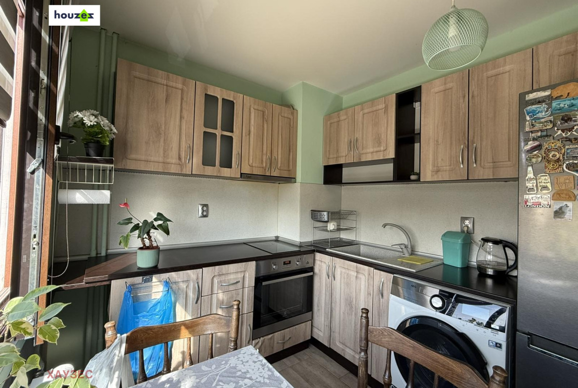 Kitchen corner with wood upper and lower cabinets, black countertop, oven, sink