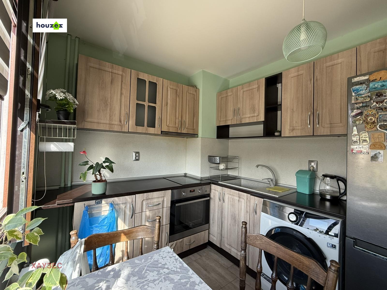 Kitchen corner with wood upper and lower cabinets, black countertop, oven, sink