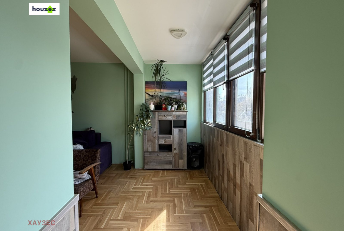 Enclosed balcony with wood panel walls, large windows, storage cabinet, green walls