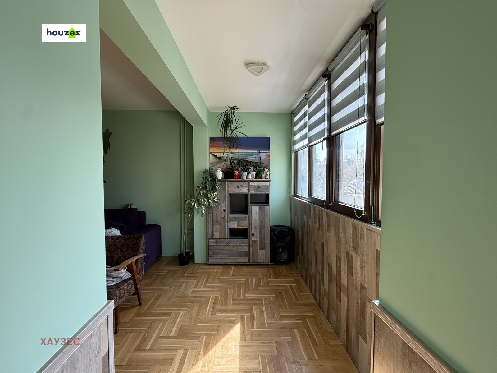 Enclosed balcony with wood panel walls, large windows, storage cabinet, green walls