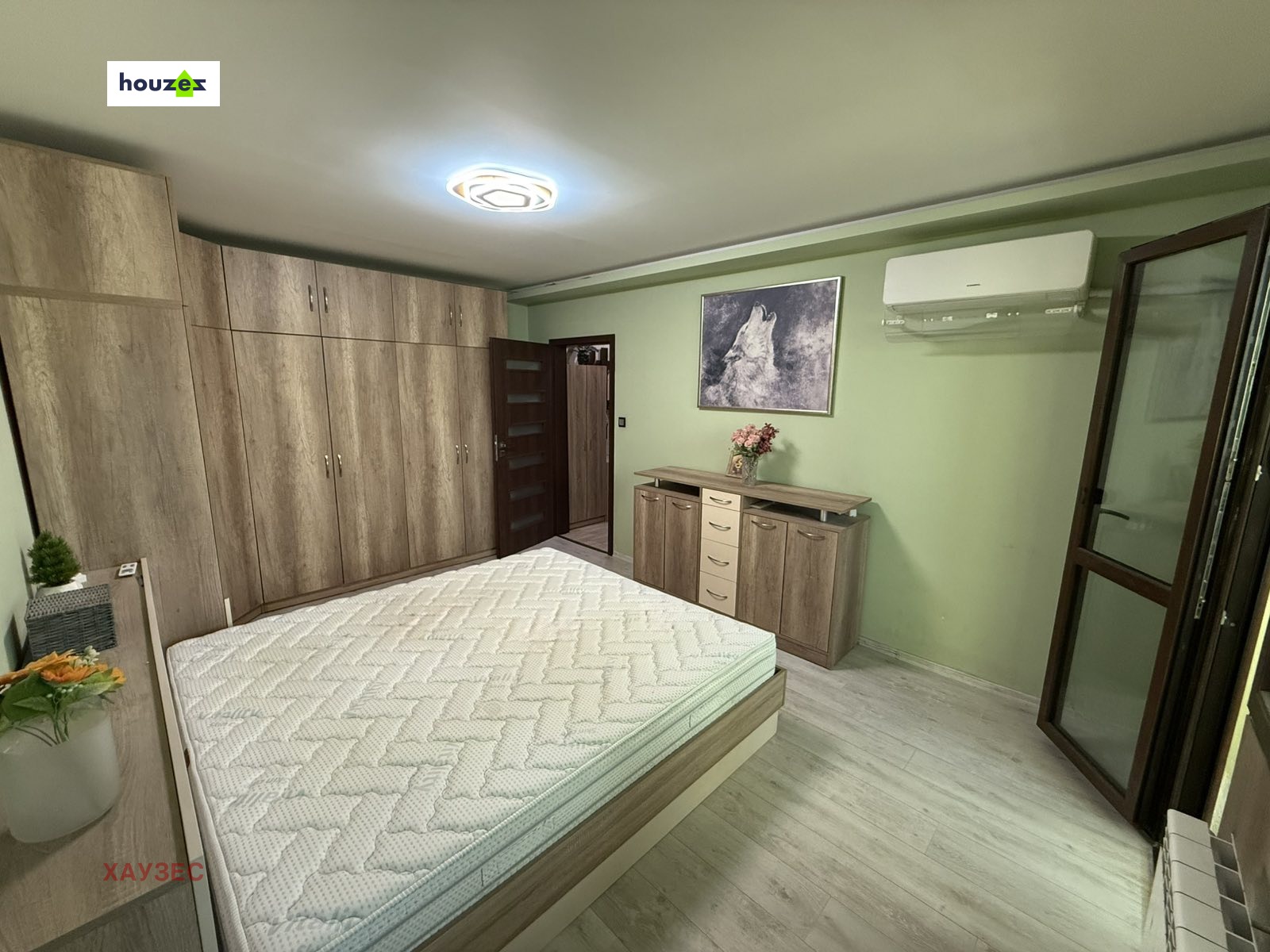 Bedroom with large wood wardrobe, double bed, dresser, wolf artwork, air conditioner