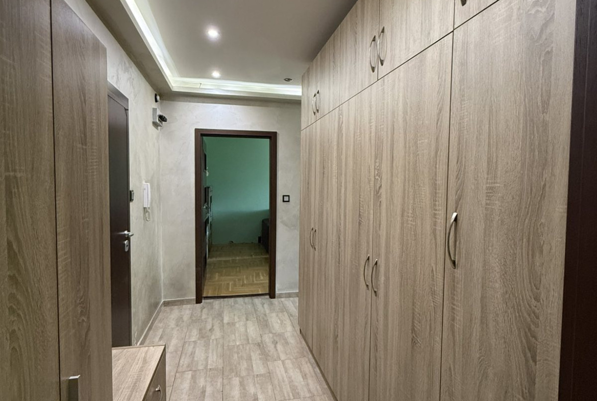 Hallway with full-length built-in wood wardrobes, recessed ceiling lights, tiled floor