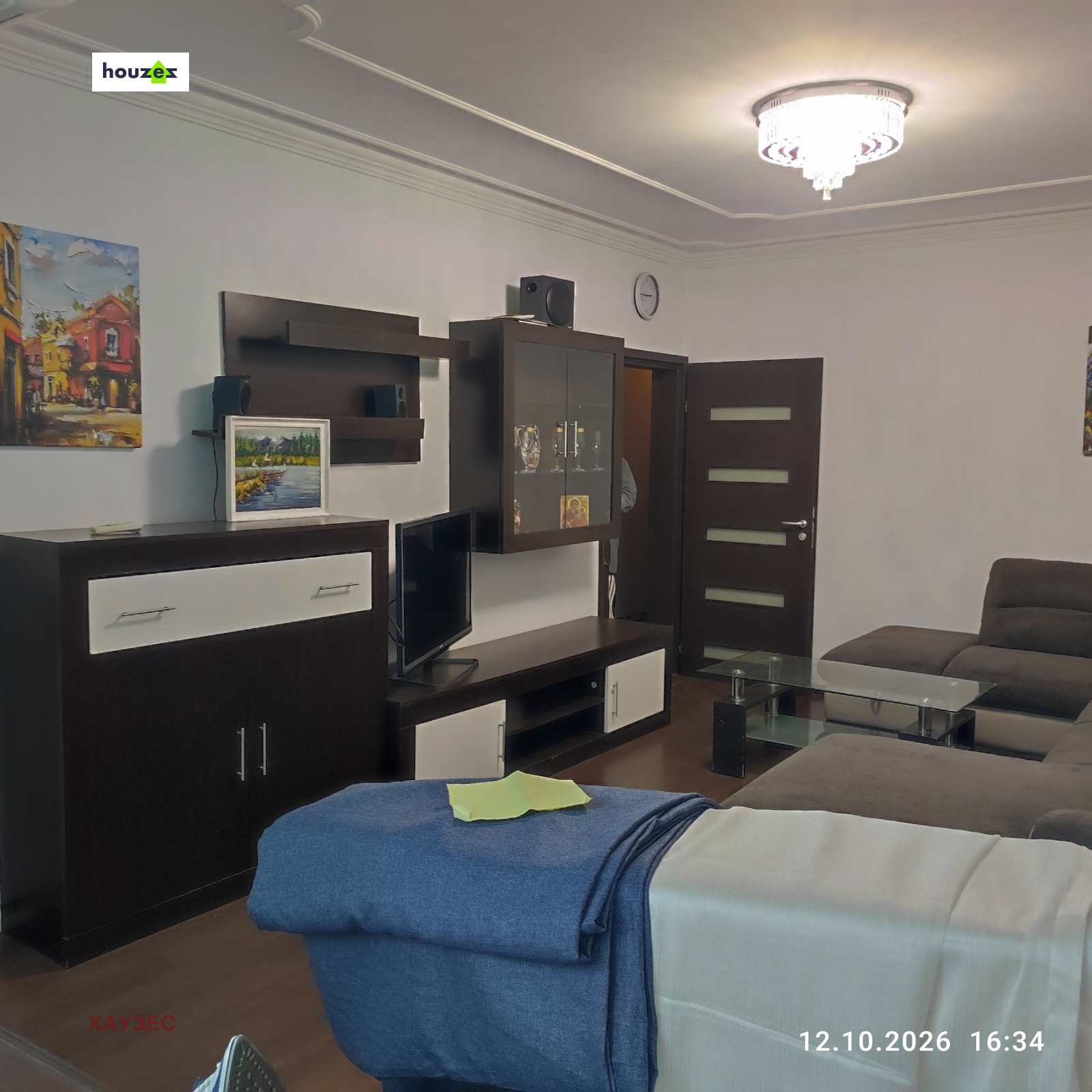 One-Bedroom Apartment in Sofia, living room with dark wall unit, TV, sofa, chandelier