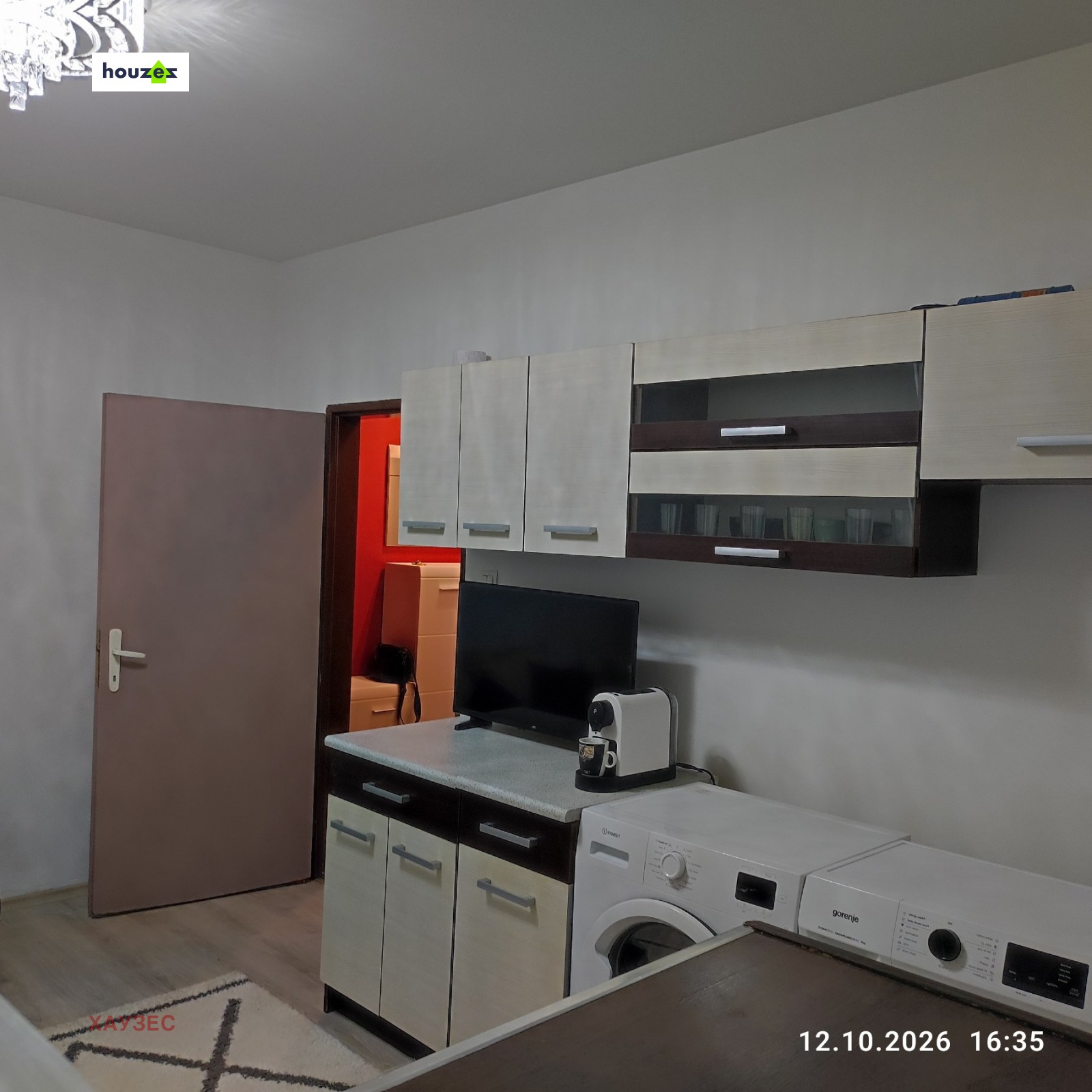 Kitchen with wall cabinets, small TV, washing machine, and dryer