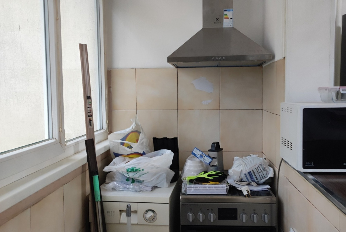 Small kitchen with electric cooker, extractor hood, microwave, beige wall tiles