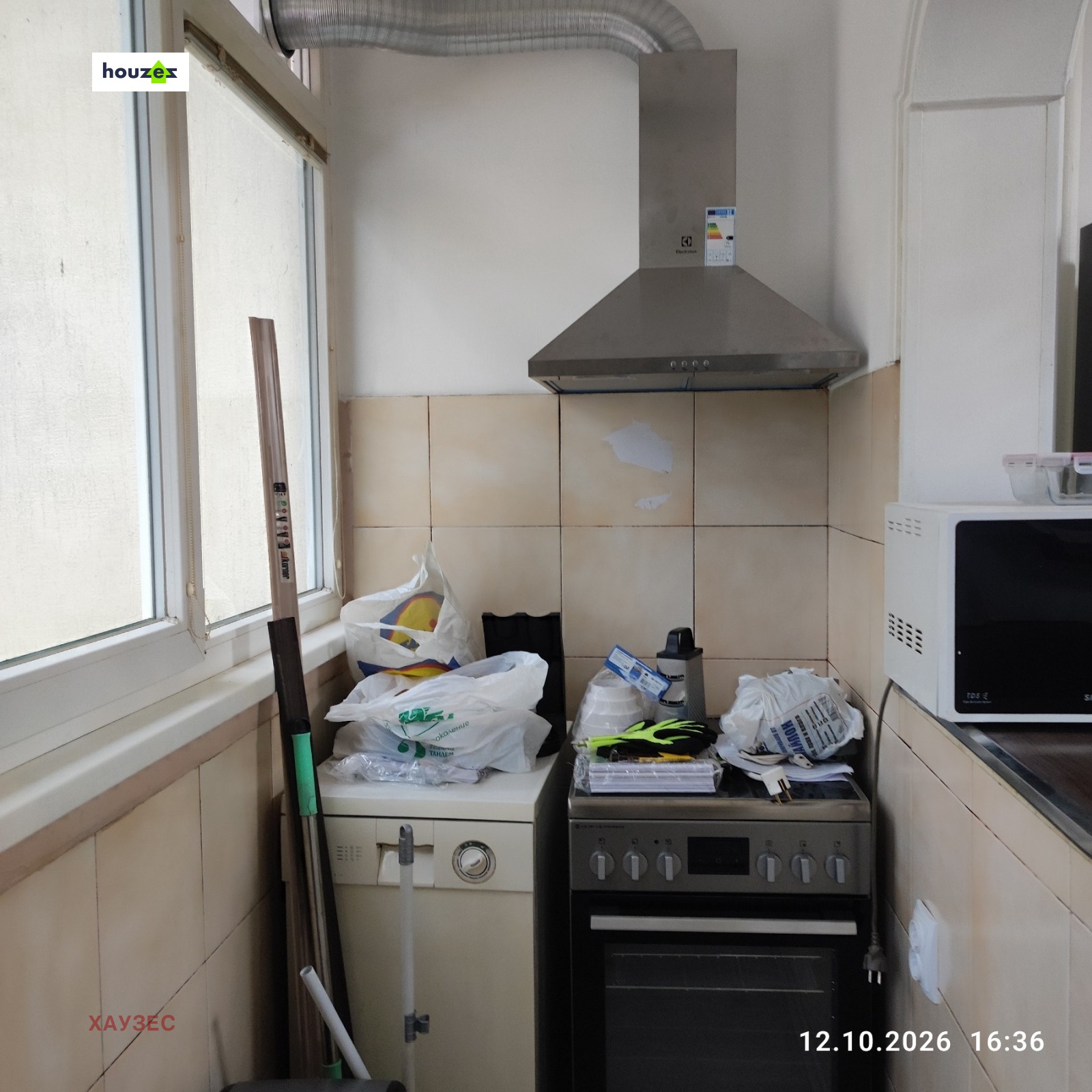 Small kitchen with electric cooker, extractor hood, microwave, beige wall tiles
