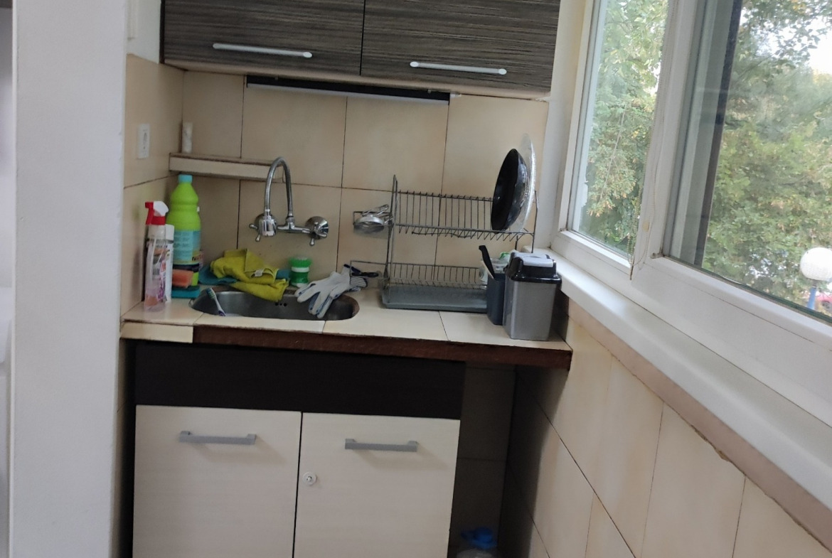 Kitchen sink corner with upper cabinets, tile backsplash, and garden window